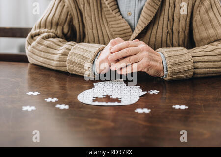 7/8-Ansicht der pensionierte Mann spielt mit Rätseln auf Tisch Stockfoto
