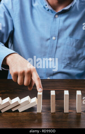 7/8-Ansicht des Menschen verhindern, Holzklötze von sinkenden mit Finger Stockfoto