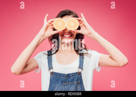 Lächelnde Frau mit Orangen über Augen isoliert auf Rosa Stockfoto