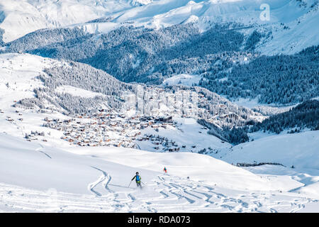 Schöne schneebedeckte Berge mit das Dorf Arosa. Zurück Langläufer im Vordergrund hinterlassen ihre Spuren in den tiefen Schnee. Stockfoto