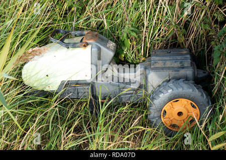 Brocken Childrens Ride-on Traktor gedumpten am Straßenrand Stockfoto