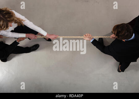 Rivalisierende business Mann und Frau konkurrieren für den Befehl durch Ziehen am Seil Stockfoto