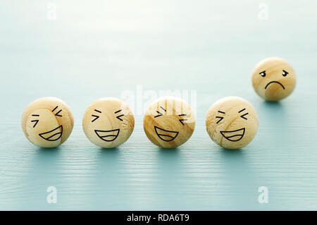 Begriff des Mobbing, Diskriminierung. Gruppe lachender Smiley Faces und eine allein Schauen traurig und deprimiert Stockfoto