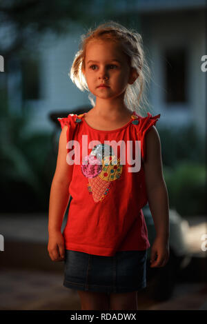 Porträt von einem hübschen blonden Mädchen draußen an einem warmen Sommerabend, die Sonne beleuchtet die Haare von hinten. Stockfoto