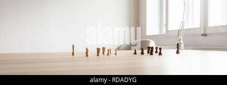 In der breiten Ansicht Bild von Schwarzen und Weißen Schachfiguren auf Holz- büro Schreibtisch einander gegenüber in einem konzeptionellen Bild platziert. Stockfoto