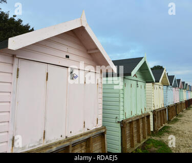 Eine Reihe von pastellfarbenen Badekabinen, geschlossen für den Winter entlang Mudeford Strand, Dorset, England, Januar 2019. Stockfoto