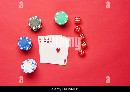 Ein Winning Poker Hand von vier Asse Spielkarten passt auf rotem Hintergrund mit Chips und Würfel. Stockfoto
