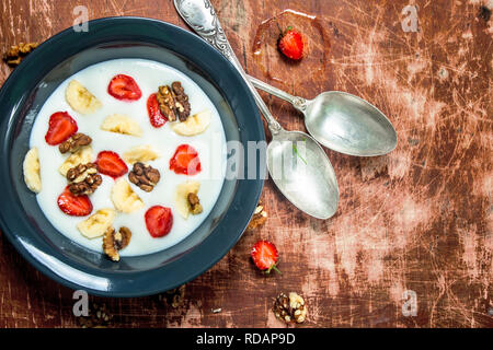 Grieß Brei mit Erdbeeren und Muttern. Auf rustikalen Hintergrund. Stockfoto