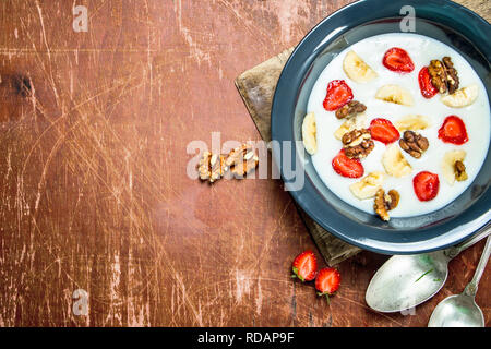 Grieß Brei mit Erdbeeren und Muttern. Auf rustikalen Hintergrund. Stockfoto