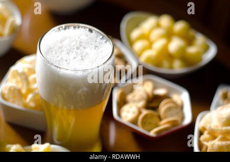 Pint Lager Bier im Glas, der verschiedene Snacks, einen Standardsatz von Essen und Trinken in einer Kneipe, Bier und Snacks Stockfoto