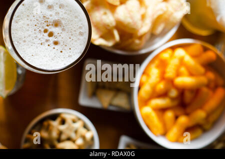 Pint Lager Bier im Glas, der verschiedene Snacks, einen Standardsatz von Essen und Trinken in einer Kneipe, Bier und Snacks Stockfoto