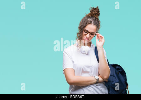 Junge brünette Studentin Mädchen mit Rucksack und Kopfhörer über isolierte Hintergrund denken müde und mit Depressionen Probleme mit Cr gelangweilt Stockfoto