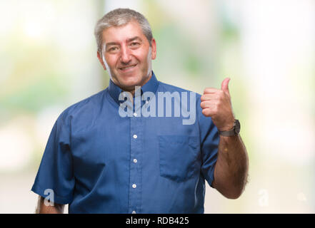 Gut aussehender älterer Mann über isolierte Hintergrund lächelnd mit glücklichen Gesicht und zeigt auf die Seite mit dem Daumen nach oben. Stockfoto