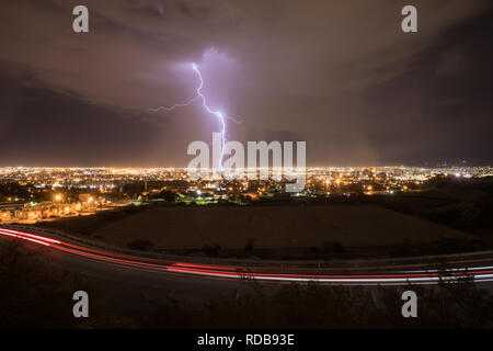 Blitzeinschläge zentrale El Paso, Texas, in einer Sommernacht, wie der Verkehr auf der Straße hinterlässt leichte Wanderwege Stockfoto
