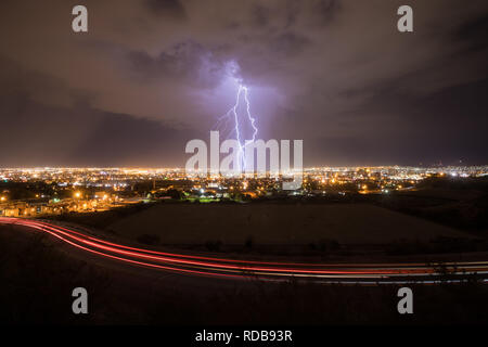 Blitzeinschläge zentrale El Paso, Texas, in einer Sommernacht, wie der Verkehr auf der Straße hinterlässt leichte Wanderwege Stockfoto