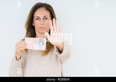 Mittleres Alter Frau mit 50 Pfund Bank Note über isolierte Hintergrund mit der offenen Hand tun, STOP-Schild mit ernsten und selbstbewussten Ausdruck, Verteidigung ge Stockfoto