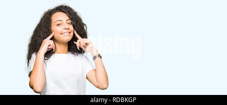 Junge schöne Mädchen mit lockigem Haar legere weißes T-Shirt lächelnd mit offenen Mund, Finger zeigen und zwingen die fröhlichen Lächeln Stockfoto