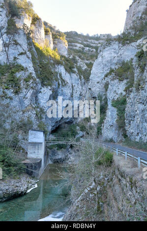 Eine gepflasterte Straße in die Veral River Canyon gehen, mit hohen grauen Felsen Schlucht bei Sonnenuntergang in Foz de Binies in ländlicher Umgebung, in Aragon, Spanien Stockfoto