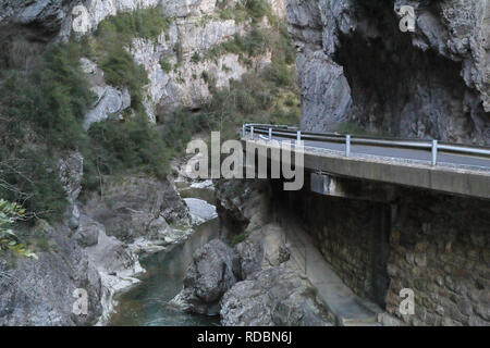 Eine gepflasterte Straße in die Veral River Canyon gehen, mit hohen grauen Felsen Schlucht bei Sonnenuntergang in Foz de Binies in ländlicher Umgebung, in Aragon, Spanien Stockfoto
