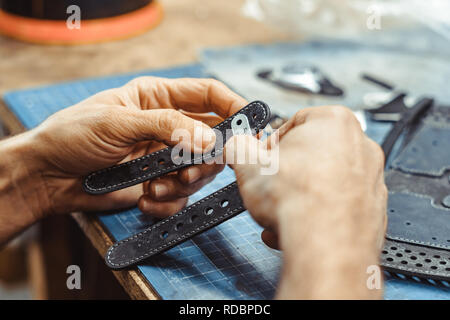 Professionelle männlichen Skinner, Tanner arbeiten mit echtem Leder Gürtel in Werkstatt, Studio. Handgemacht und Lederarbeiten Konzept Stockfoto