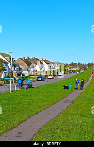 Eine junge Familie mit Hund und Kinderwagen zu Fuß entlang der Klippe Pfad in Penarth, Cardiff, Wales. Teure freistehende Häuser mit Meerblick. Stockfoto