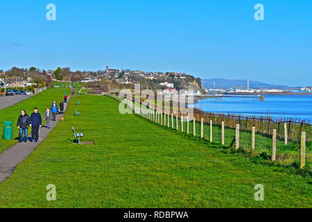 Menschen zu Fuß entlang der Klippe Wanderweg mit Blick auf das Meer in Penarth, Cardiff, Wales. Art Deco Penarth Pier in Abstand. Stockfoto