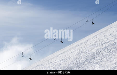 Snowy off-piste Skipiste mit Spuren von Skiern und Snowboards und Sesselbahn gegen Himmel mit Wolken im Winter Stockfoto