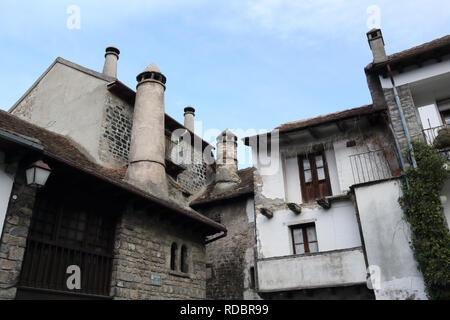 Traditionelle Häuser mit runde Schornsteine in einem Pyrenäen Dorf mit Häusern aus Stein und dunklen Dächern im Winter in Hecho, Region Aragon, Spanien Stockfoto