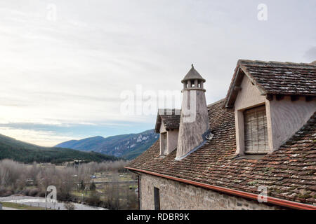 Ein traditionelles Haus dunklen Dach mit zwei Mansarde Windows, runde Schornstein in einem Pyrenäen Dorf im Winter in Hecho, Region Aragon, Spanien Stockfoto