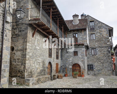 Eine ländliche Landschaft aus einem Bergdorf mit einigen Häusern aus Stein mit Holzbalkonen und dunklen Dächern im Winter in Ansó, Region Aragon, Spanien Stockfoto