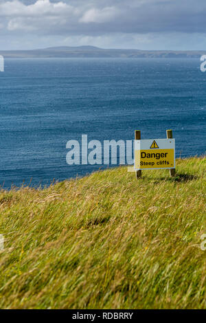 Warnschild auf steilen Felsen durch den Atlantischen Ozean, auf der Insel Lewis, Äußere Hebriden, Schottland, UK Stockfoto