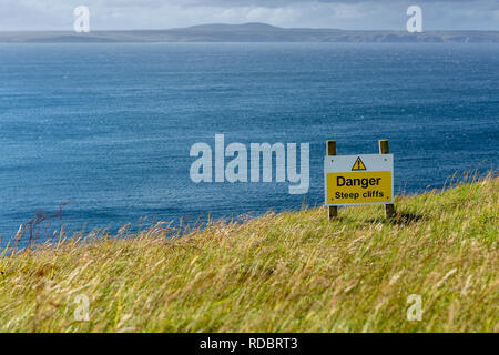 Warnschild auf steilen Felsen durch den Atlantischen Ozean, auf der Insel Lewis, Äußere Hebriden, Schottland, UK Stockfoto