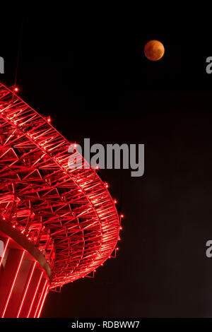 Eine seltene Super Blut Mond während der supermoon und die totale Mondfinsternis im Jahr 2018 mit einem glühenden Stadion im Hintergrund. Rot, Eclipse, seltene Stockfoto