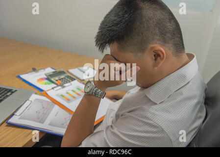 Junge Mitarbeiter fühlen sich müde und nach dem Lesen der vielen Sales Reports frustriert Stockfoto