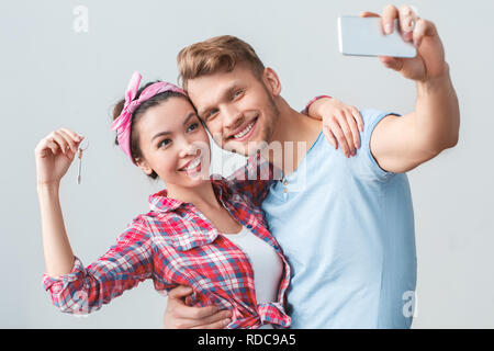 Junges Paar, der neue Ort ständigen umarmen Gedrückthalten der Taste unter selfie Fotos von fröhlichen Stockfoto