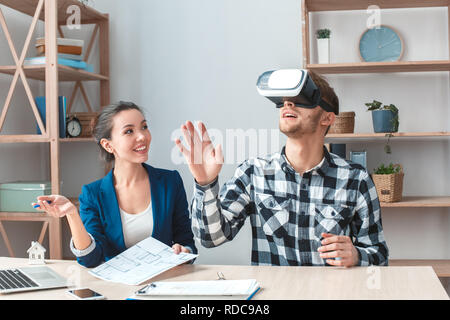 Mann an Immobilien Agentur in virtual reality Headset sitzen im neuen Haus der Freude suchen Stockfoto