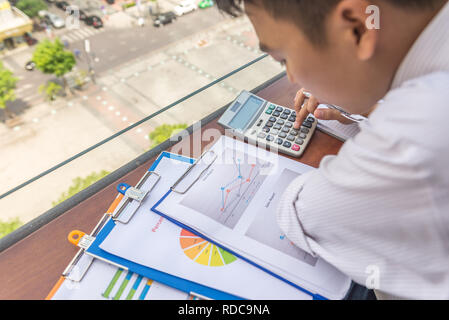 Junger Mann mit Taschenrechner Finanzberichte zu prüfen. Stockfoto