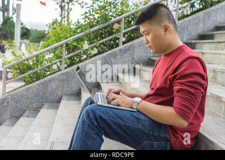 Seitenansicht des jungen asiatischen Menschen Arbeiten am Laptop Stockfoto