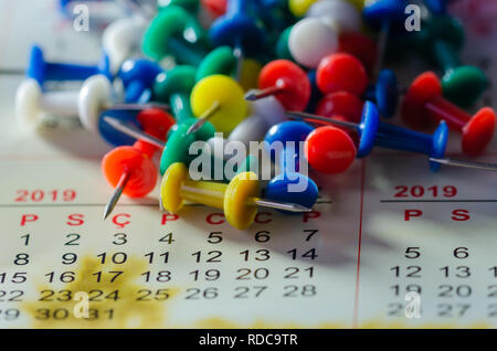 Bunte Reißzwecken auf einen Kalender. Schule oder Business Konzept Stockfoto