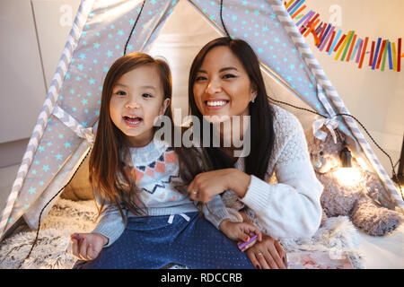 Foto eines glücklichen jungen asiatischen Frau mit ihrer kleinen Tochter Spaß auf dem Boden. Weihnachten Konzept. Stockfoto