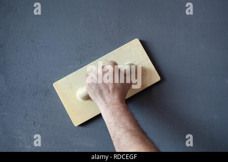 Hand mit kunststoffspachtel Verputzen und Glätten einer nassen Beton verputzte Wand. Stockfoto