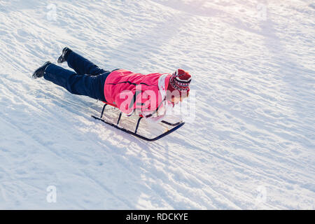 Ältere Frau Schlitten bergab. Frau Spaß auf Schlitten im Winter Park liegen. Stockfoto