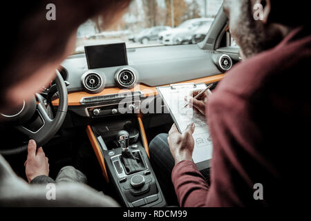 Dunkelhaarige Fahrlehrer Notizen nach test fahren Stockfoto