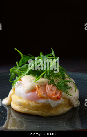 Sandwich mit pochiertem Ei, geräuchertem Lachs und Käse dekoriert mit Rucola Stockfoto