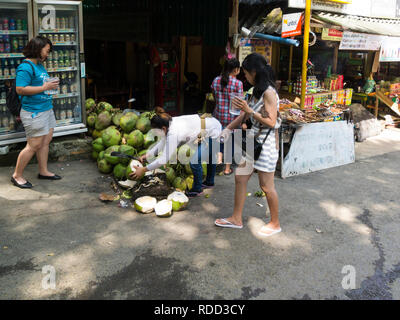 Lady Eröffnung coconut für erfrischend Trinken Essen ausserhalb Eingang Kuang Si Wasserfälle Park auch als Tat Kuang Si Wasserfällen Abschaltdruck Stockfoto