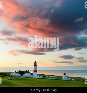 Riesige bunte dramatische Wolken sind erleuchtet von den Sonnenuntergang über Souter Leuchtturm an der nordöstlichen Küste. Stockfoto