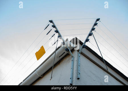 Eine Nahaufnahme der elektrischen Zäune rund um die obere Seite eines weißen Gebäude Stockfoto