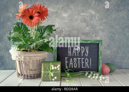 Frühling Blumen, Ostern Dekorationen und eine Tafel mit weißer Tisch. Text "Frohe Ostern!" Auf einer Tafel. Stockfoto