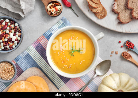 Kürbis, Bohnen und Süßkartoffeln creme Suppe in Keramik Schüssel, Ansicht von oben mit Zutaten und Gewürze Stockfoto