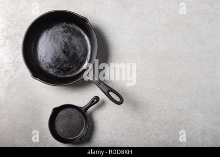 Mehrere Gusseisen Pfannen oder Skillets für gesundes Kochen auf grauem Hintergrund Stockfoto